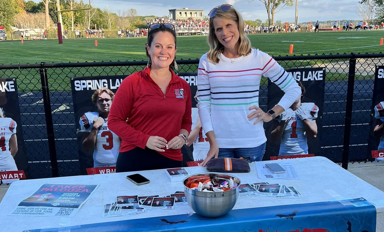 Two volunteers at the Foundation's Lakerpalooza table beside the football field