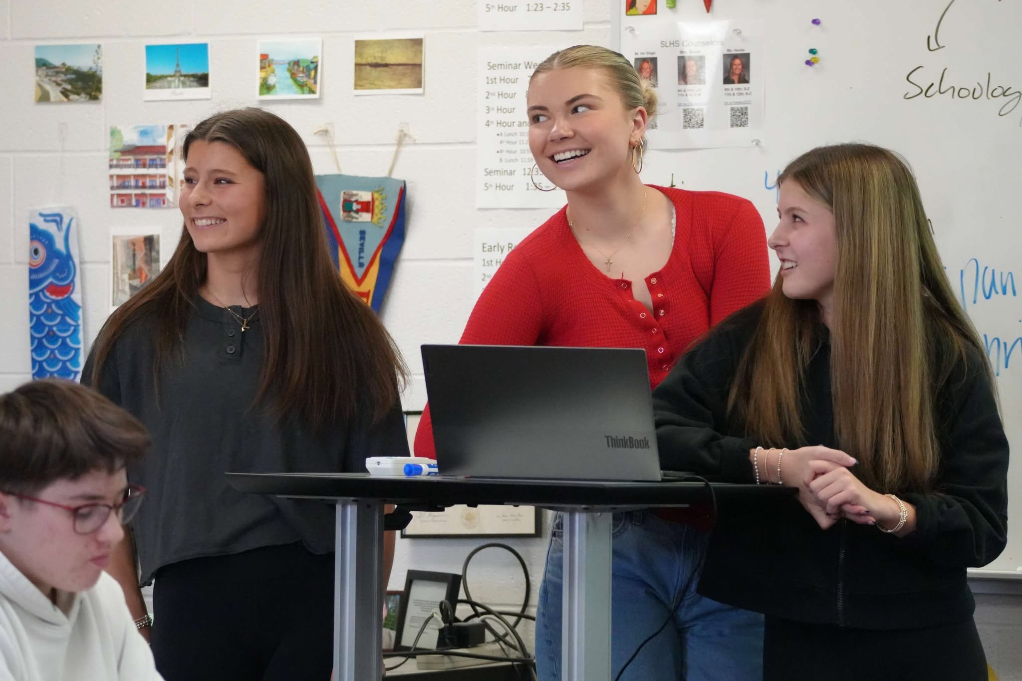 Three students presenting at the front of a classroom