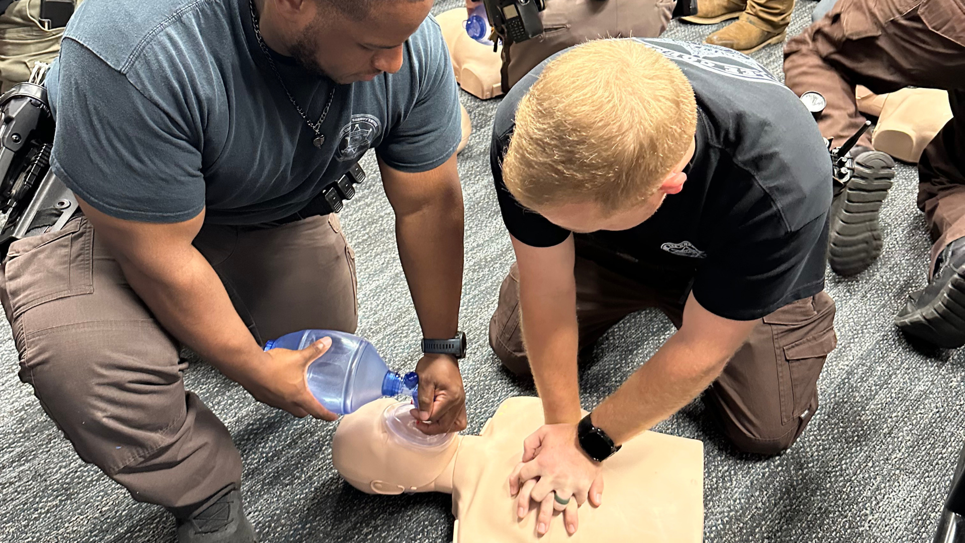 Two trainees practicing CPR on a manikin during a certification class