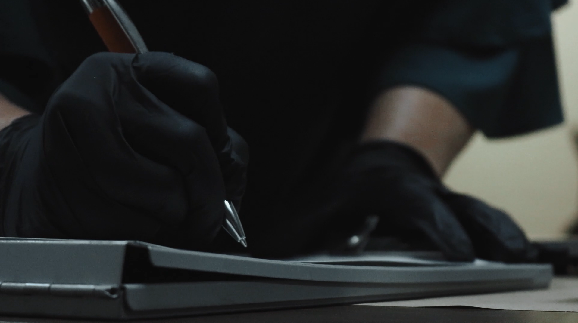 Investigator wearing black gloves writing notes on a clipboard